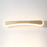 Curved wood and acrylic vanity light lit on a plain white wall