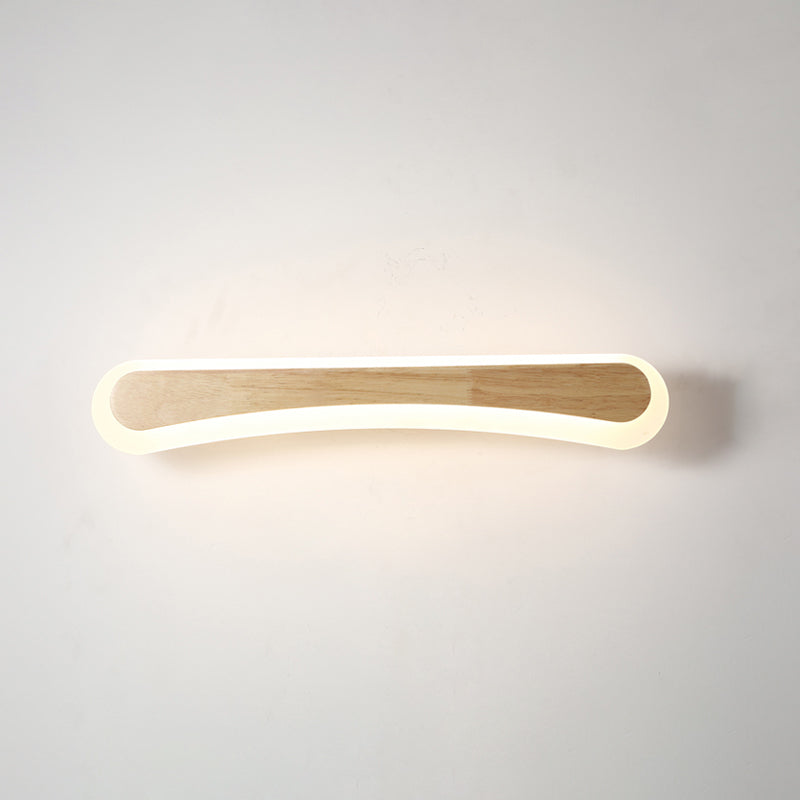 Curved wood vanity light lit against a plain pale wall
