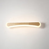 Curved wood vanity light lit against a plain pale wall