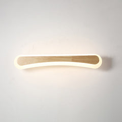Curved wood vanity light lit against a plain pale wall