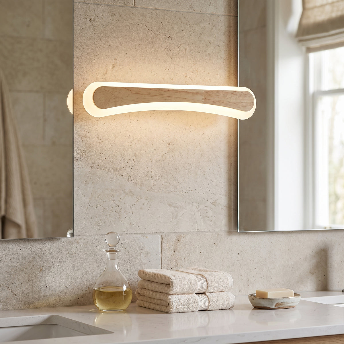Curved wood vanity light lit on a travertine bathroom wall