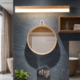 Straight wood vanity light above a round mirror on a slate wall