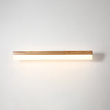 Straight wood vanity light lit against a plain pale wall