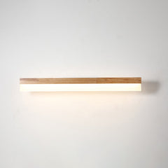 Straight wood vanity light lit against a plain pale wall