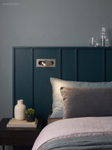 Recessed bedside reading light in a dark green panelled bedhead wall