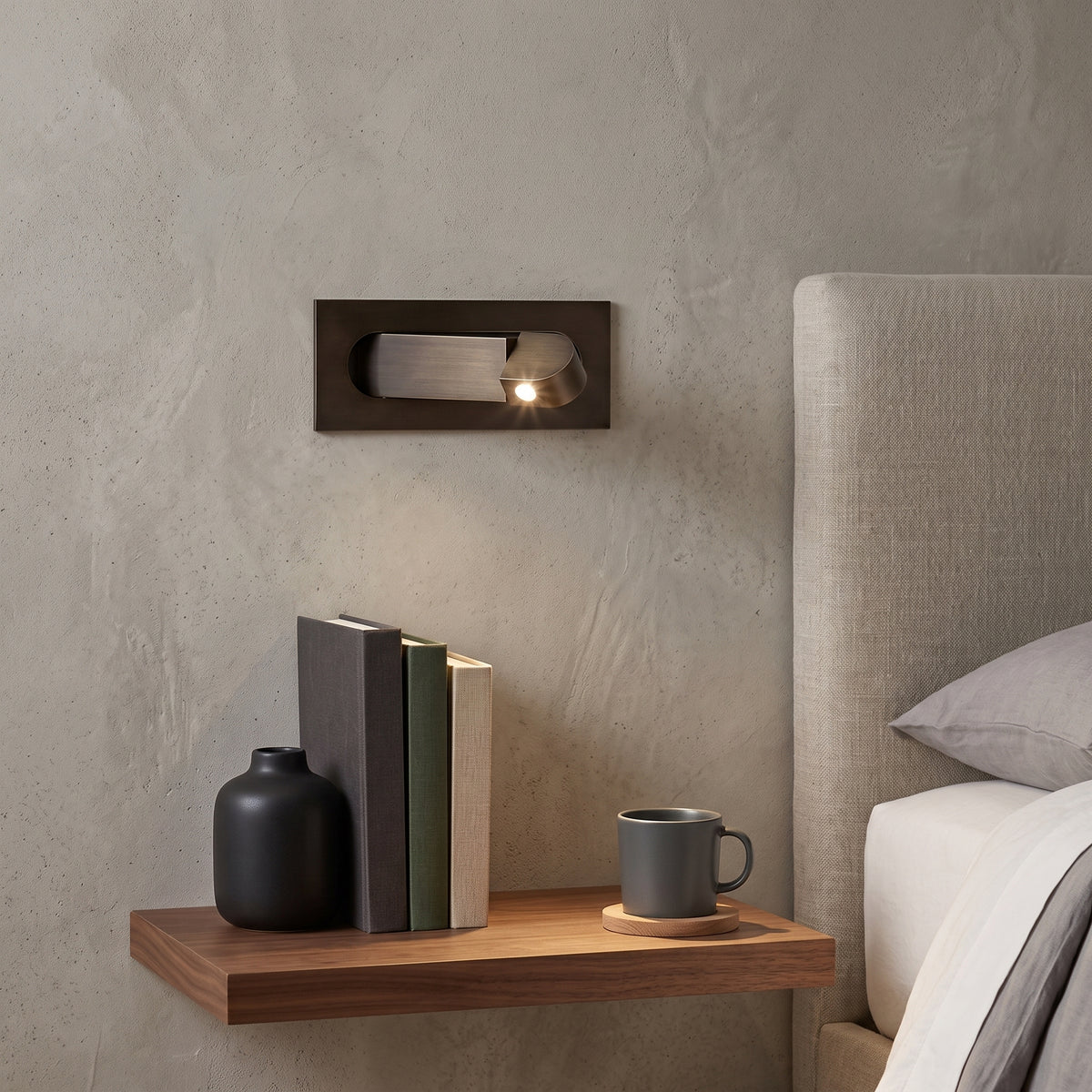 Bronze bedside reading wall sconce above a timber shelf and bed