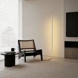 White corner floor lamp glowing beside a cane chair and wall mounted television