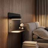 Black rotating wall lamp with shelf beside a bed and sofa