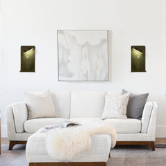 Two wall lamps flanking wall art with directional beams over a sofa
