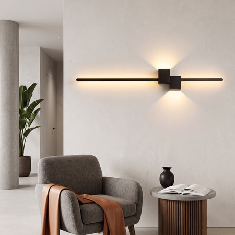 Black linear LED wall sconce glowing above a grey armchair