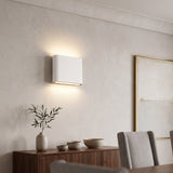 White rectangular LED wall sconce lit warm above a walnut sideboard