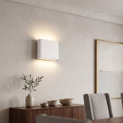 White rectangular LED wall sconce lit warm above a walnut sideboard