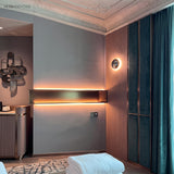 Mirrored dome sconce lit on a bedroom wall beside a teal curtain