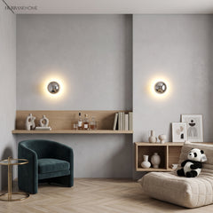 Two mirrored dome sconces lit on a pale wall above a bench seat