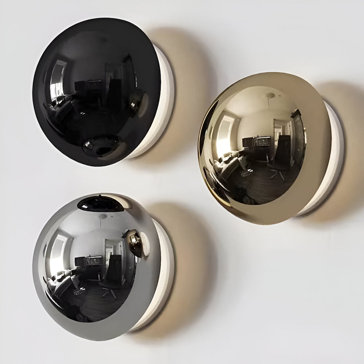 Black gold and silver dome sconces grouped on a white surface
