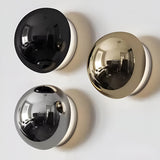 Black gold and silver dome sconces grouped on a white surface