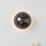 Silver dome sconce lit on a white wall with a soft ring of light