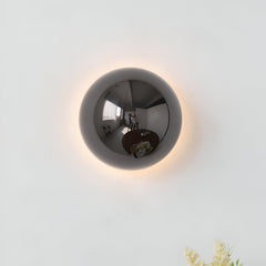 Silver dome sconce lit on a white wall with a soft ring of light