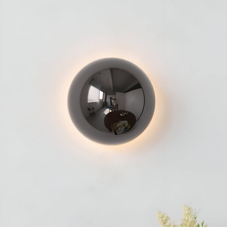 Silver dome sconce lit on a white wall with a soft ring of light