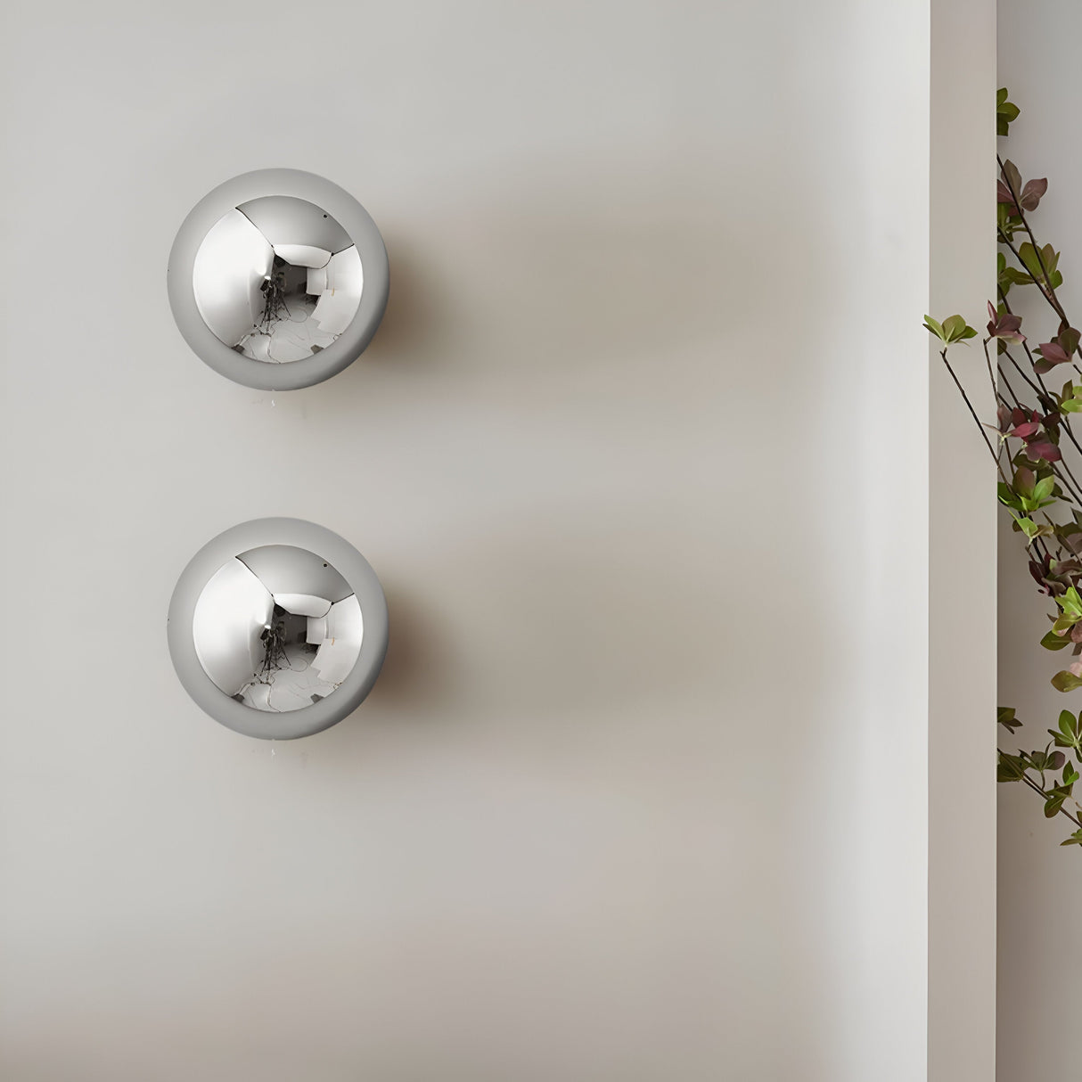 Two small silver dome sconces stacked on a white wall