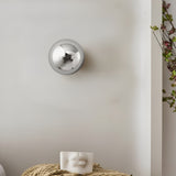 Silver dome sconce lit beside a hanging plant on a white wall