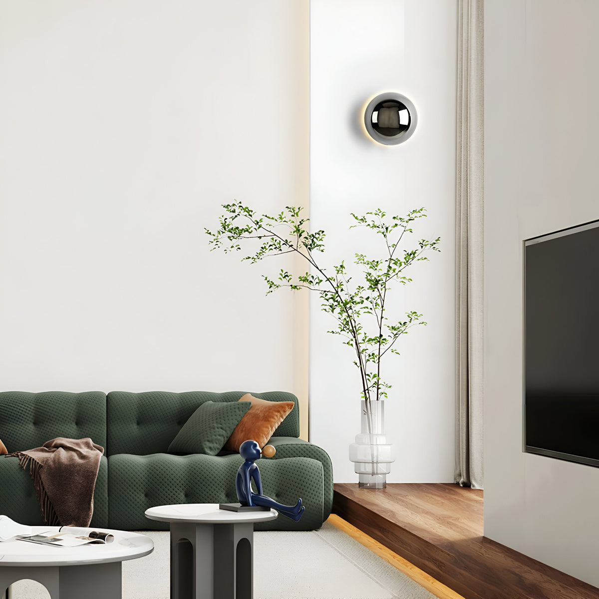 Silver mirrored dome sconce lit beside a green sofa in daylight