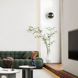 Silver mirrored dome sconce lit beside a green sofa in daylight