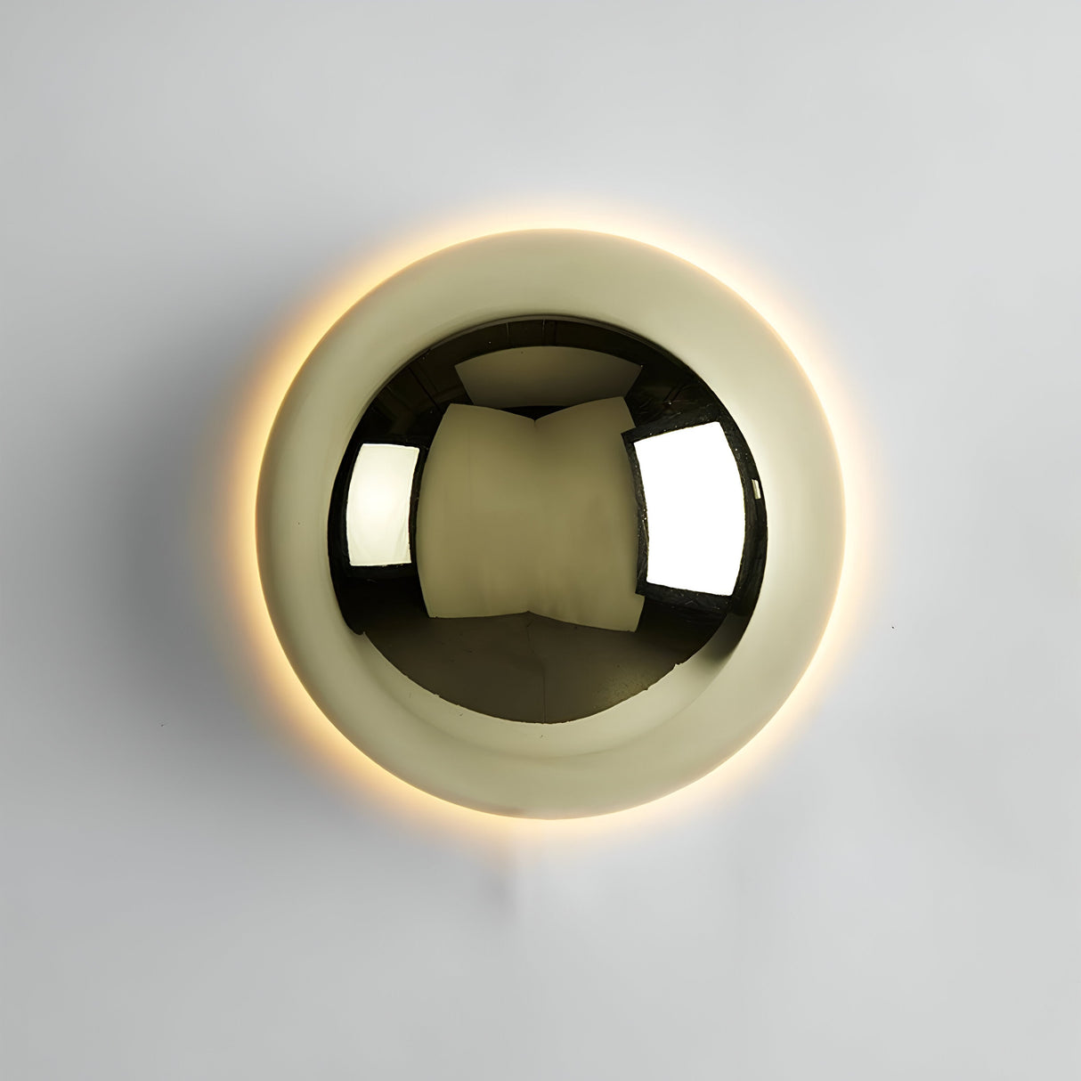 Large gold dome sconce lit on a white wall showing the halo ring