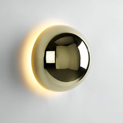 Large gold dome sconce lit on a white wall above a low table