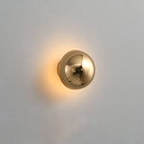 Black mirrored dome sconce lit on a pale grey wall
