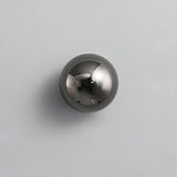 Black dome sconce lit on a white wall beside a dark headboard