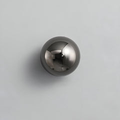 Black dome sconce lit on a white wall beside a dark headboard