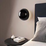Gold dome sconce lit on a white wall with a strong halo ring