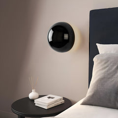 Gold dome sconce lit on a white wall with a strong halo ring