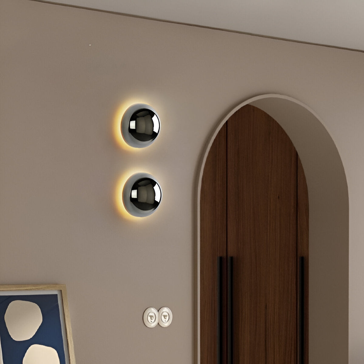 Two silver dome sconces on a beige wall beside an arched doorway