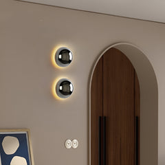 Two silver dome sconces on a beige wall beside an arched doorway