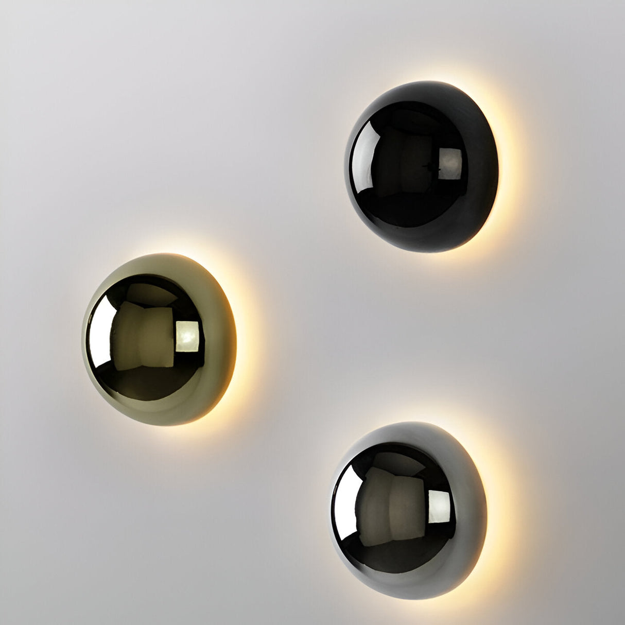 Three dome sconces in black gold and silver on one white wall