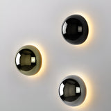 Three dome sconces in black gold and silver on one white wall