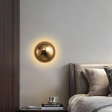 Gold dome sconce lit above a bedside table with books