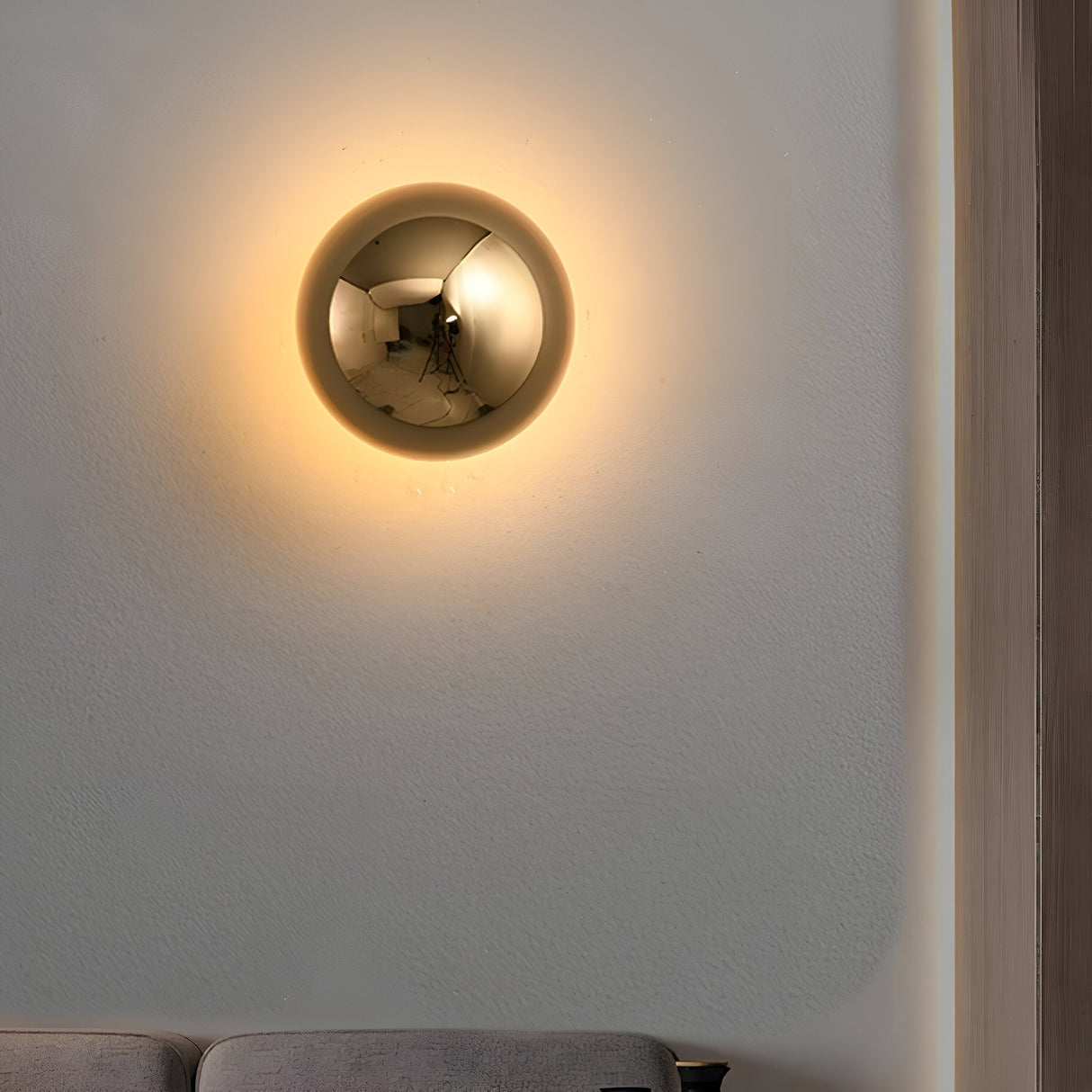 Gold dome sconce lit on a white wall in a bright room