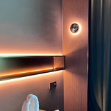 Silver dome sconce lit against a dark timber and neon interior