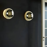 Two silver dome sconces lit on a dark painted door wall