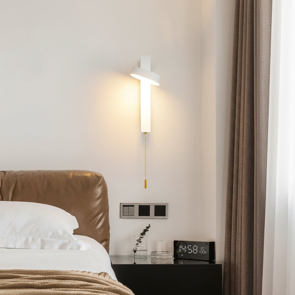 White rotating sconce lit beside a bed and a bedside clock