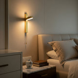 Gold bar sconce with a rotating disc head lit against white