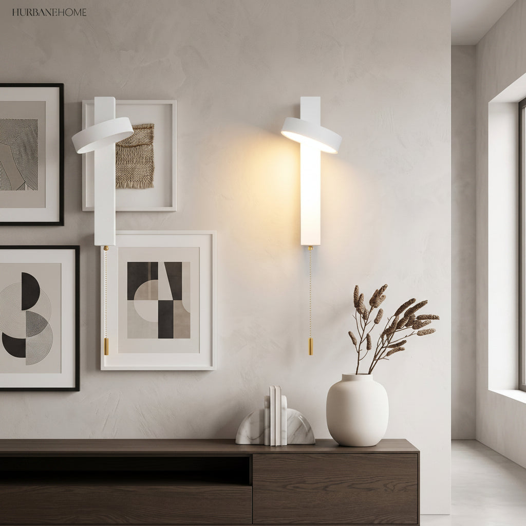 White rotating sconce lit above a sideboard beside framed prints