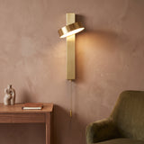 Gold rotating wall sconce with a pull chain on a terracotta wall
