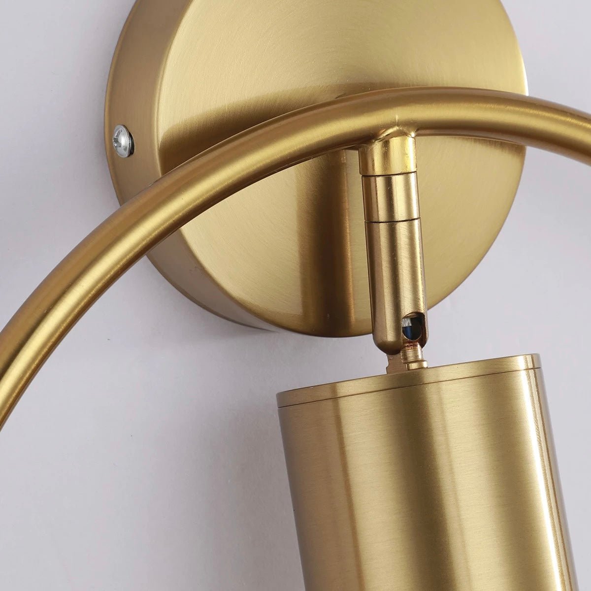 Close view of the brass arm meeting the round wall backplate