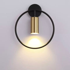 Black ring wall sconce with a brass spot lit on a pale wall
