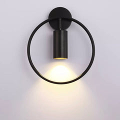 Black ring wall sconce with a black spot lit on a pale wall