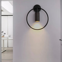 Black ring wall sconce lit on a white wall in a doorway
